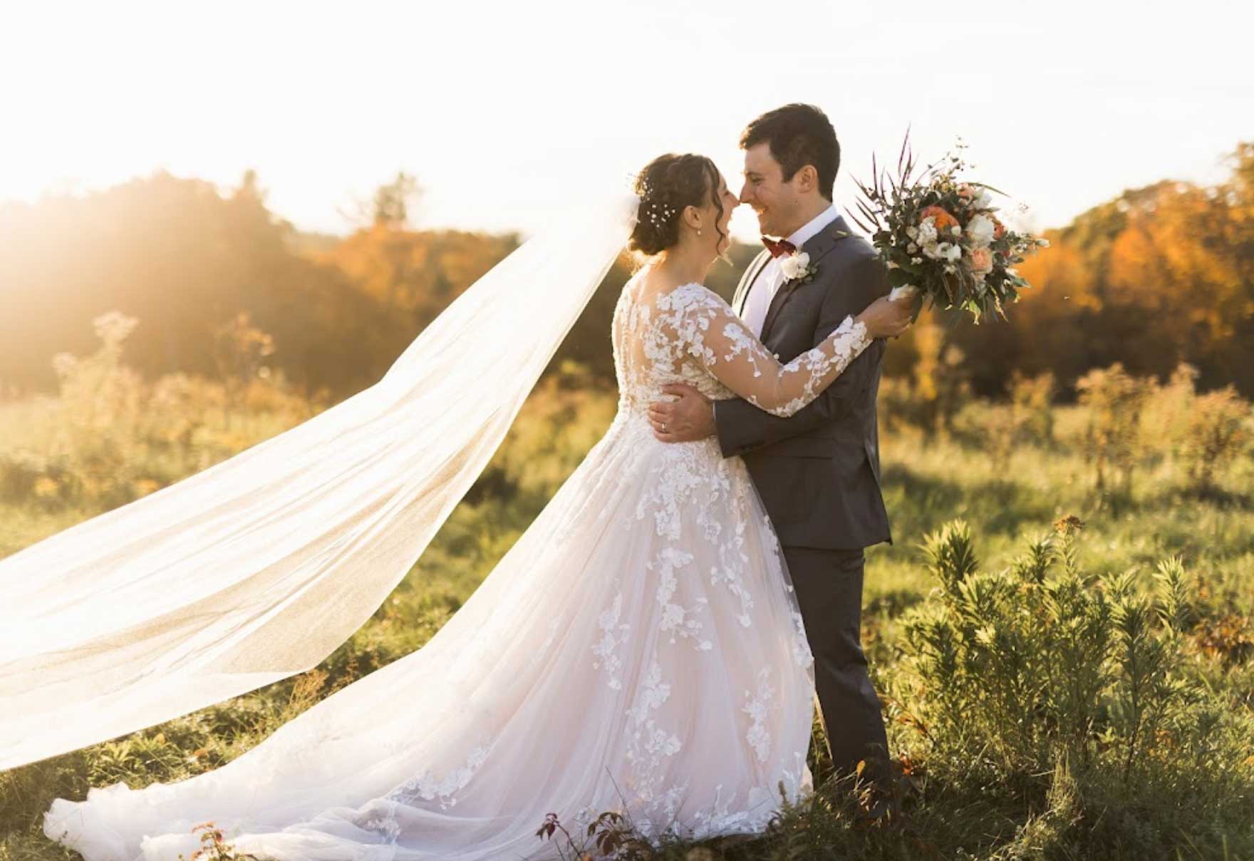 A bride and groom embrace in a field at sunset, capturing the essence of their special day.