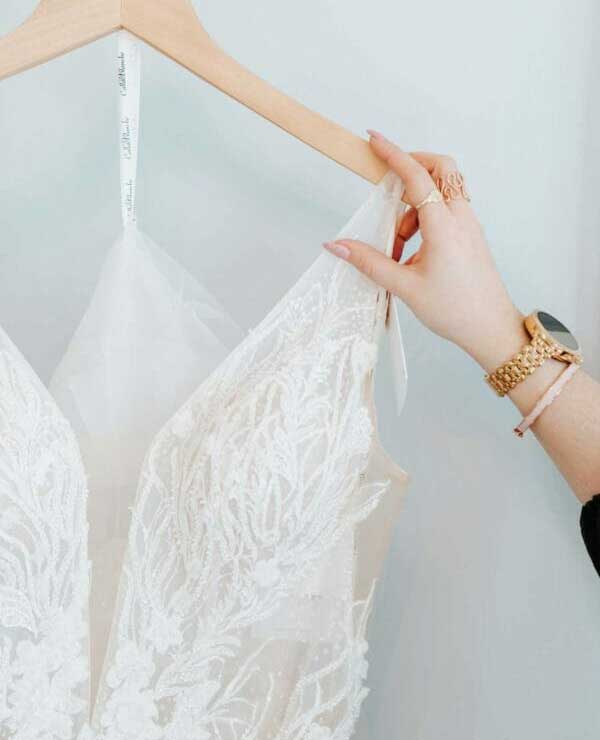 A woman is holding a wedding dress on a hanger.