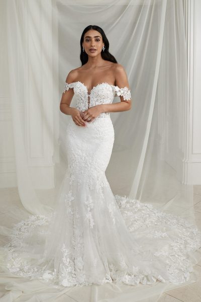 Woman wearing a lace, off-the-shoulder, fit-and-flare wedding gown (wedding dress trends)