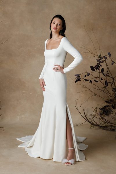 Woman wearing a simple wedding dress with a short slit and long sleeves (wedding dress trends)