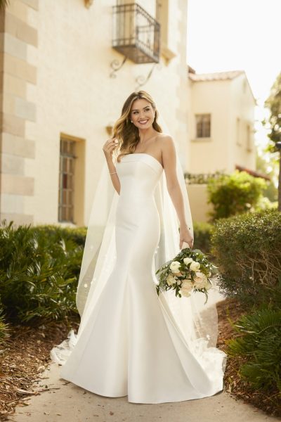 Woman wearing a simple fit and flare wedding dress and a long veil (wedding dress trends)