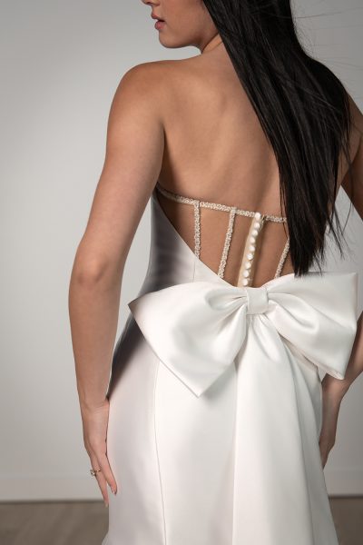 Back view of a woman wearing a wedding dress with a sheer back and a big bow (wedding dress trends)