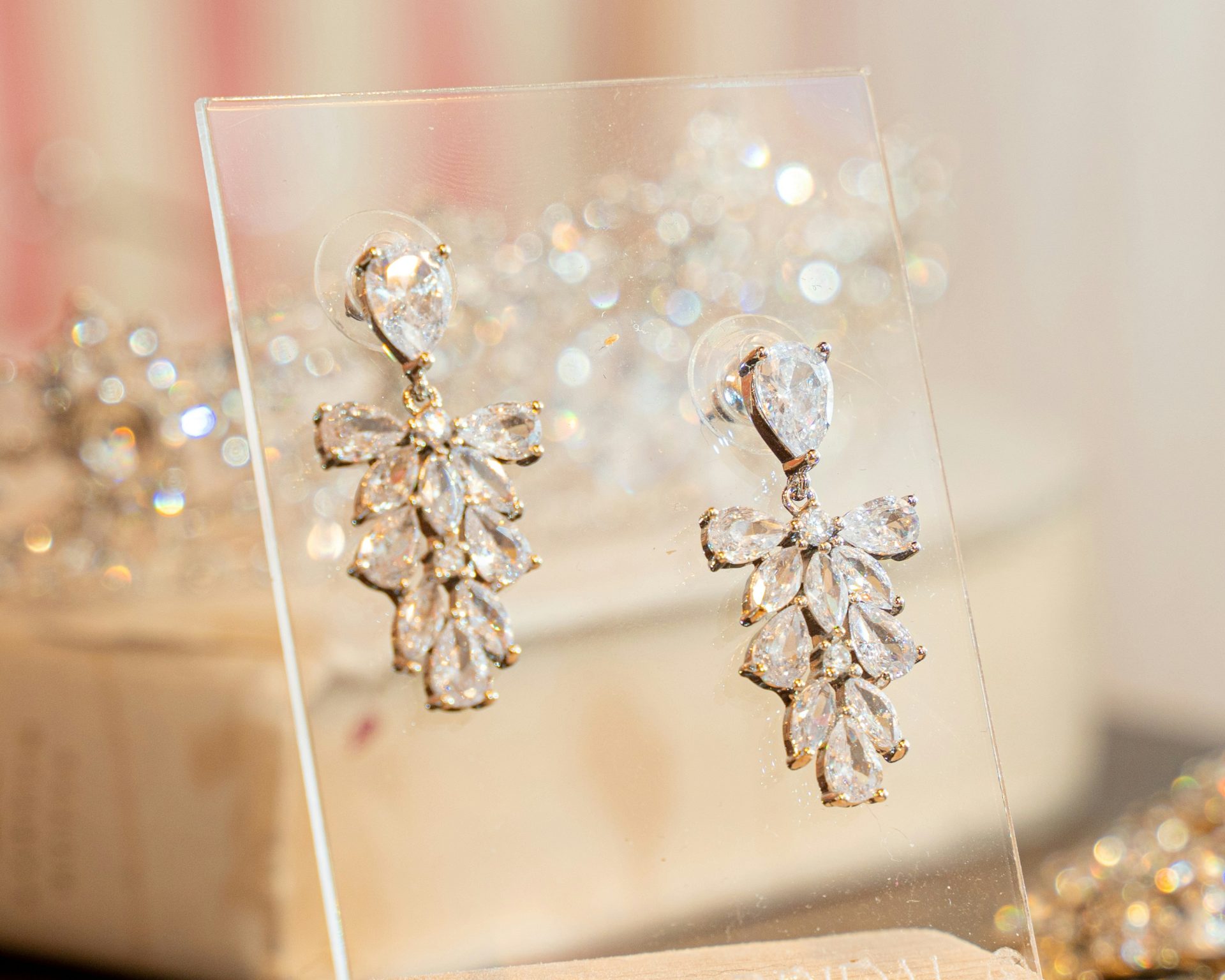 Dangly crystal earrings on a clear, plastic display. (Bridal accessories)