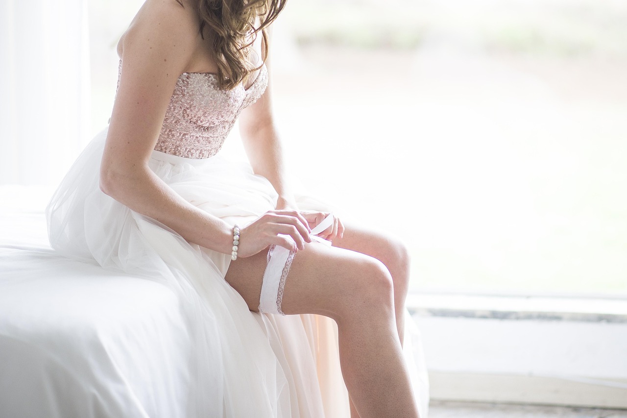 A bride putting a garter belt on her leg. (bridal accessories)